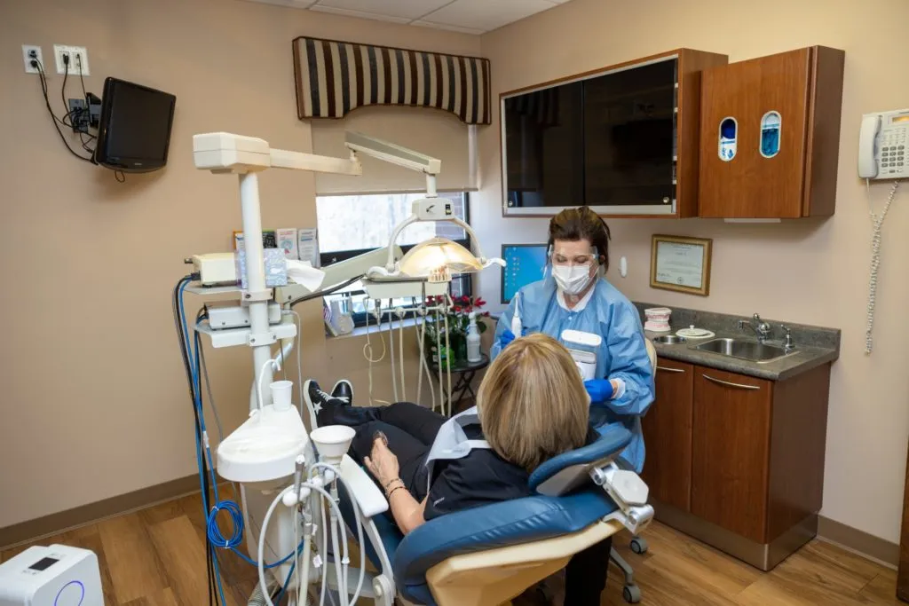 Picture depicting one of Zeal Dental's rooms featuring one of the staff members working with a patient