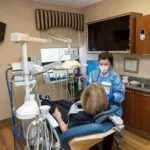 Picture depicting one of Zeal Dental's rooms featuring one of the staff members working with a patient